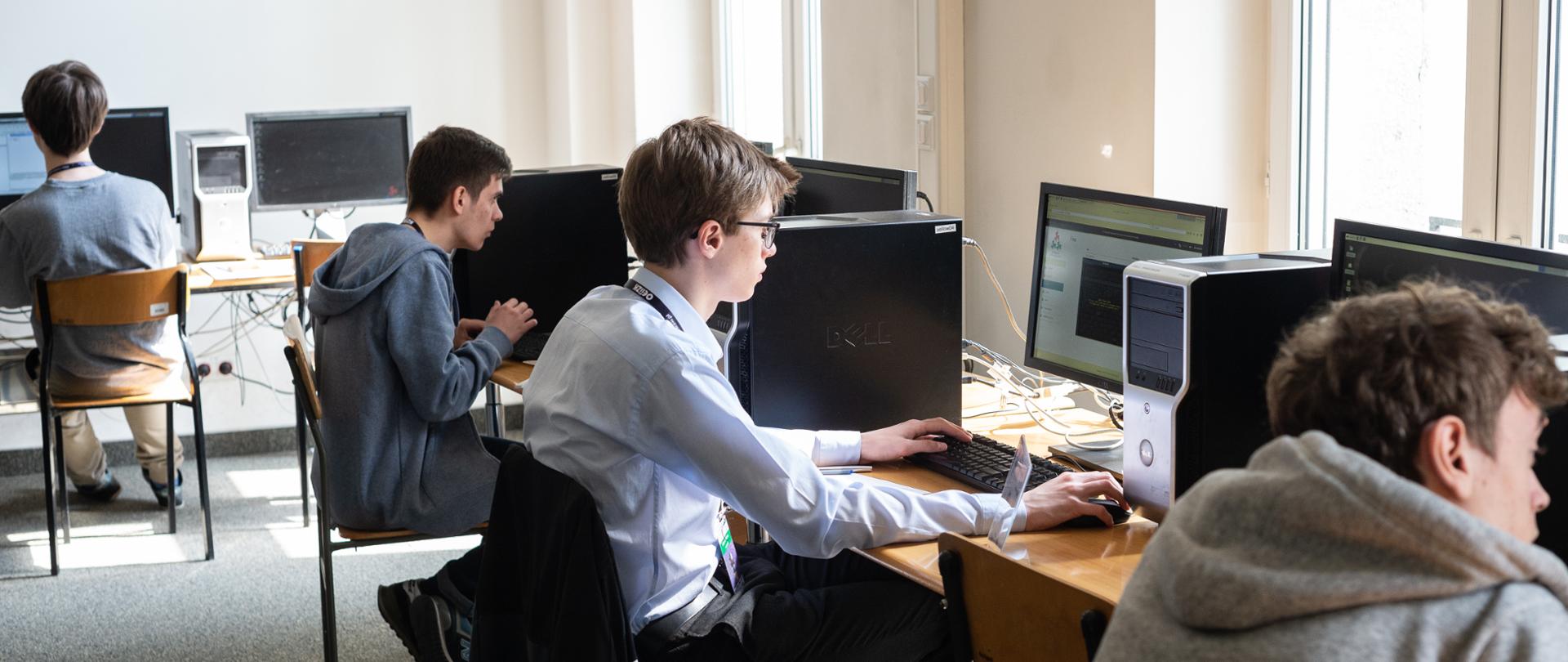 Kilka osób siedzących przed komputerami podczas Olimpiady Informatycznej