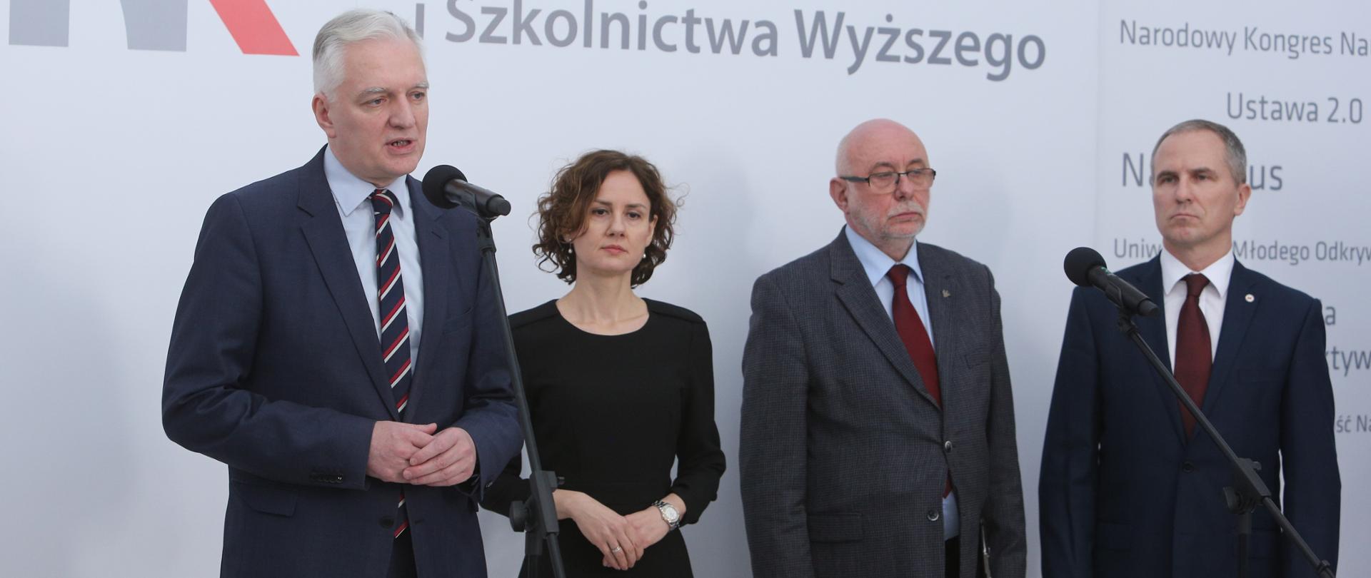 Na zdjęciu widać przemawiającego do mikrofonu wicepremiera Jarosława Gowina. Na scenie, obok premiera, stoją Izabela Żmudka, zastępca dyrektora NCBR oraz dwóch rektorów.