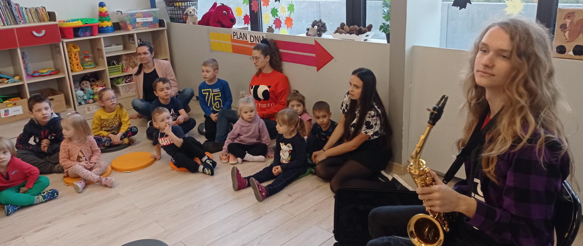 zdjęcie - dzieci z przedszkola oglądają prezentowany instrument przez ucznia PSM I stopnia - Filipa Zapłotyńskiego. fot. A. Skowrońska