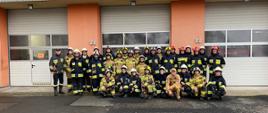 na zdjęciu widać strażaków – słuchaczy kursu w ubraniach specjalnych, w tle garaż JRG