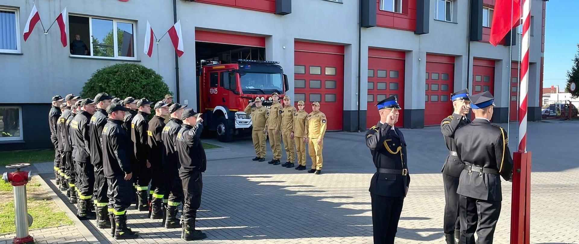 Strażacy w pododdziałach odśpiewują hymn, jednocześnie podnosząc Flagę Państwową na maszt