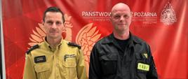 Zdjęcie przedstawia p.o. Komendanta Powiatowego PSP w Wolsztynie stojącego wraz z st. ogn. Danielem Milerem. W tle baner w kolorze czerwonym z napisem Państwowa Straż Pożarna.