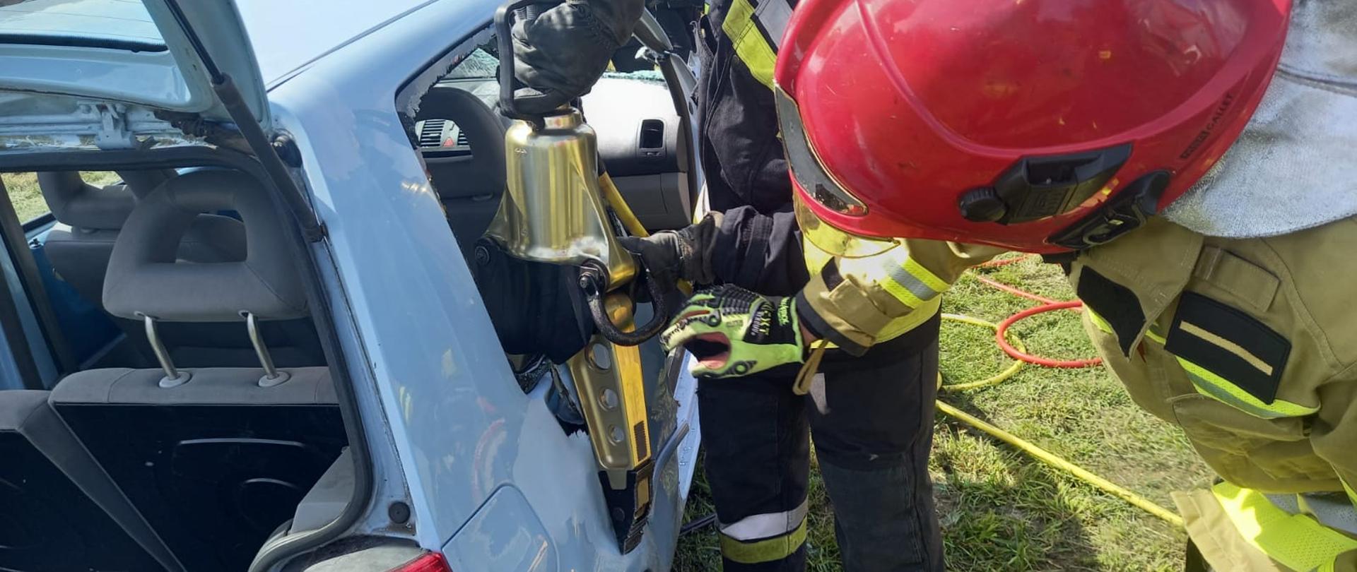 Działania praktyczne z zakresu ratownictwa technicznego, strażacy tną pojazd urządzeniami hydraulicznymi.
