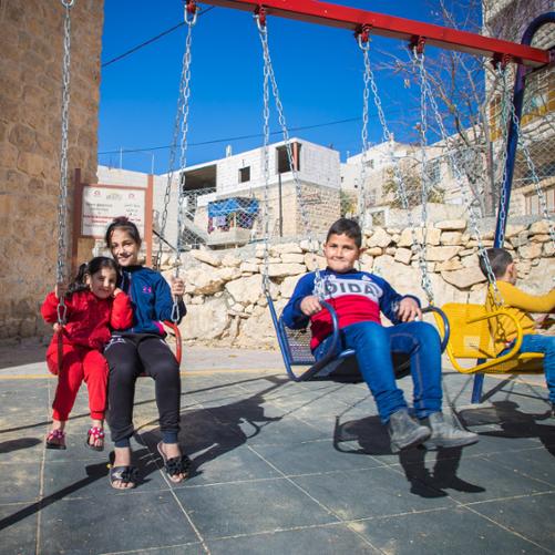 dzieci na placu zabaw siedzą na huśtawkach