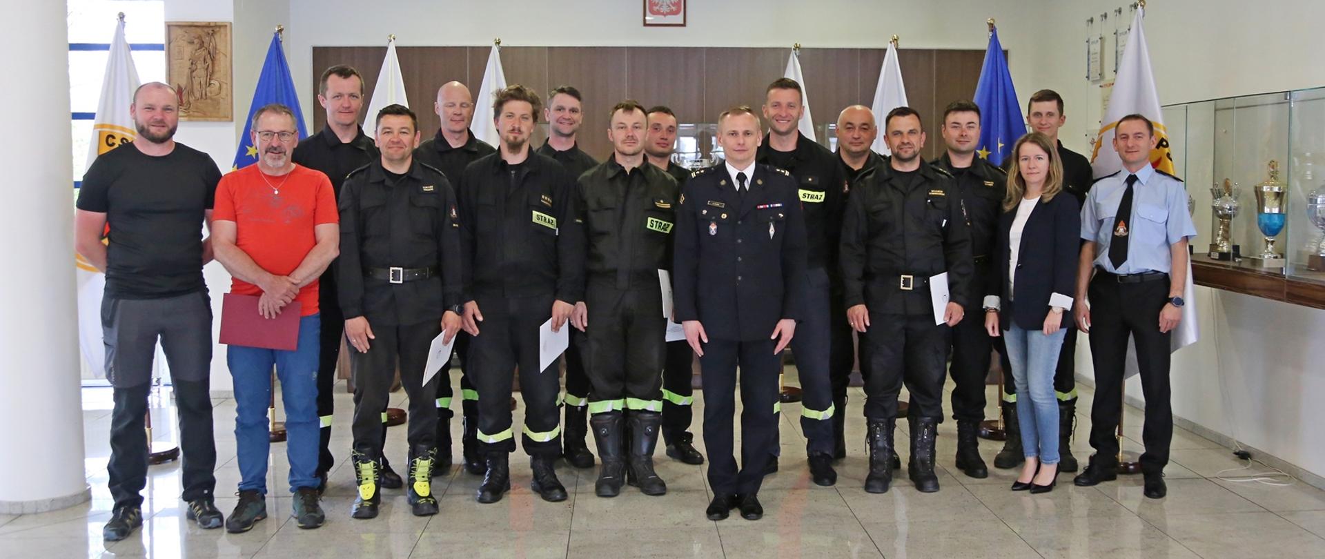 Grupowe zdjęcie uczestników warsztatów (12 osób) w towarzystwie Zastępcy Komendanta Centralnej Szkoły PSP oraz instruktorów (2 osoby) i pracowników Szkoły (2 osoby)
