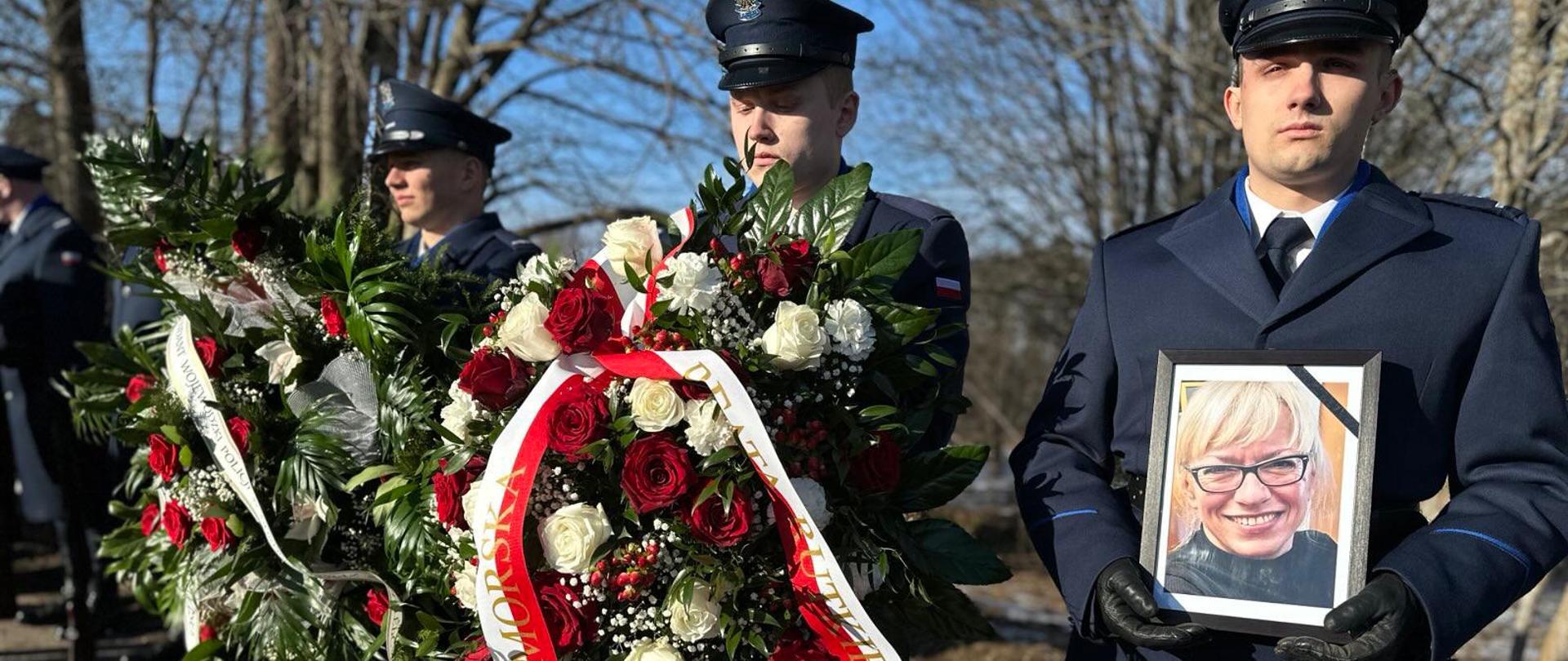 policjanci trzymają zdjęcie zmarłej i kwiaty