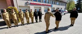 Pan komendant przed remizą PSP w Pleszewie wita się z załogą jednostki, ustawioną przed budynkiem na placu w szeregu