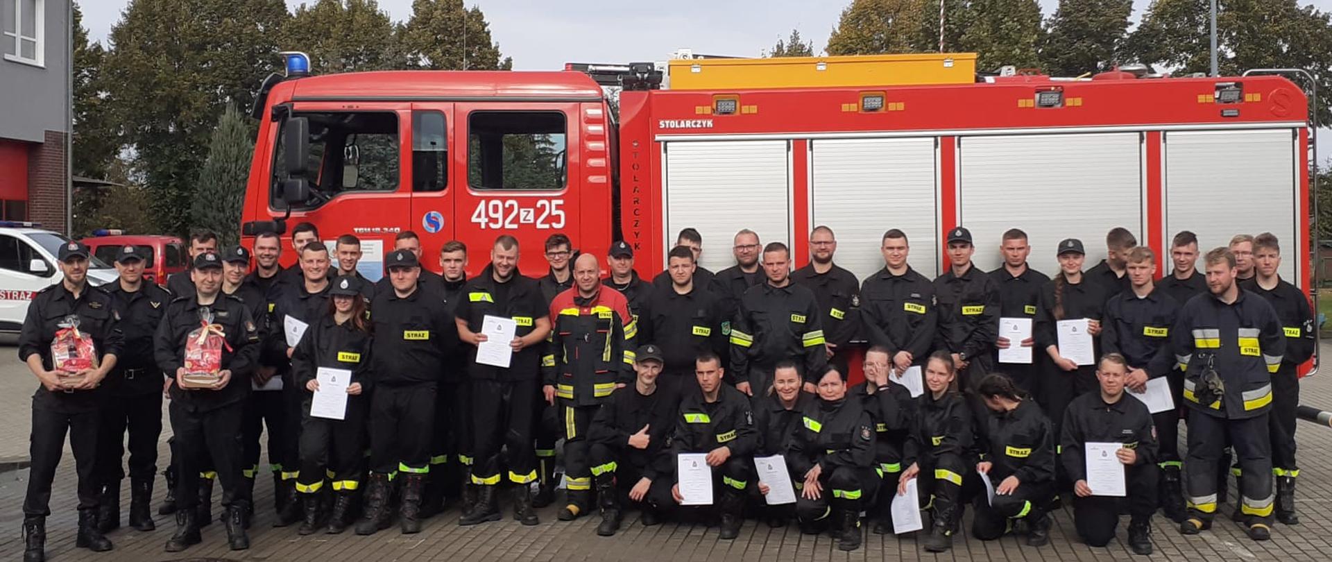 Zdjęcie przedstawia strażaków ze świadectwami ukończenia szkolenia podstawowego strażaków ratowników OSP.