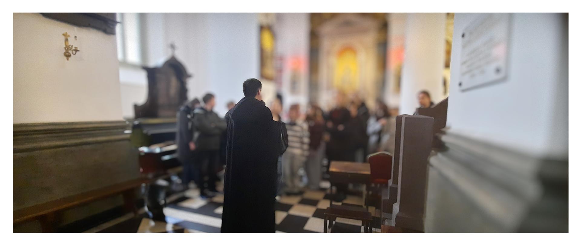 grupa ludzi w kościele stojąca przed księdzem