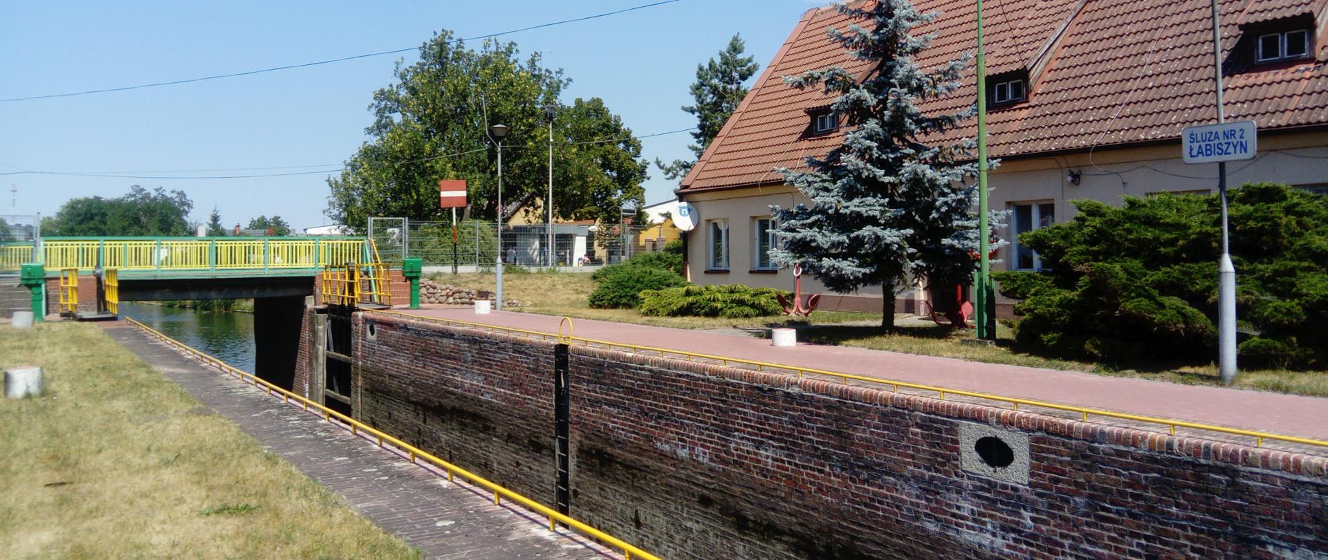 Druga śluza (Łabiszyn) na Górnonoteckim odcinku drogi wodnej Warta – Kanał Bydgoski. Śluza jednokomorowa o napędzie ręcznym i elektrycznym położona w samym centrum Łabiszyna. Po prawej stronie budynek mieszkalny oraz umieszczona na słupie nazwa Śluza Nr 2 Łabiszyn. W oddali most w kolorze żółto-zielonym oraz otwarte wrota śluzy oczekującej na płynącą łódź. 