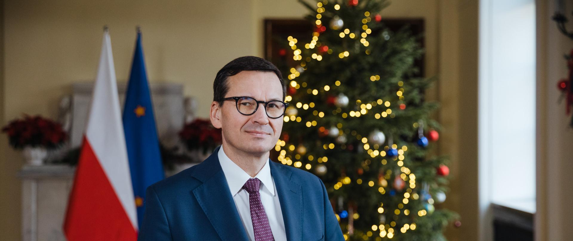 Premier Mateusz Morawiecki na tle choinki.