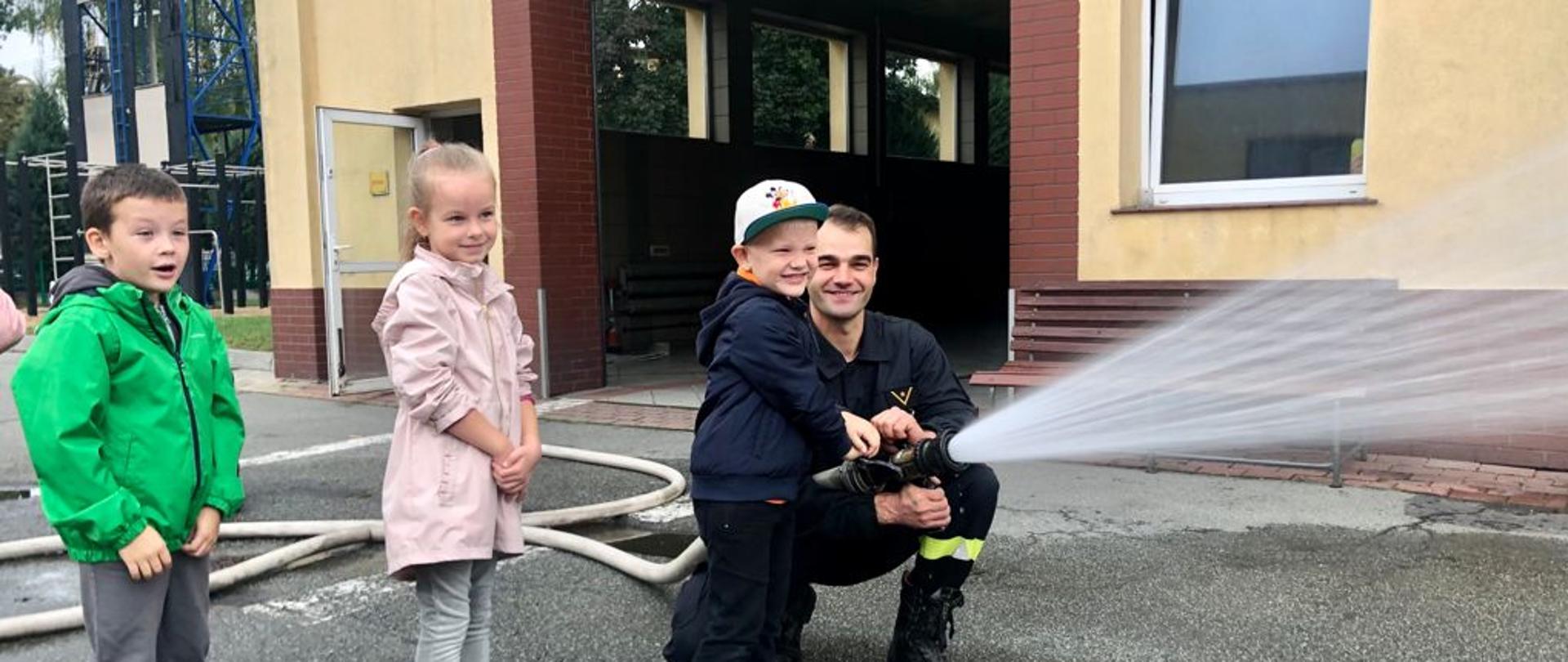 Nauka operowania prądami wody w asyście strażaka.