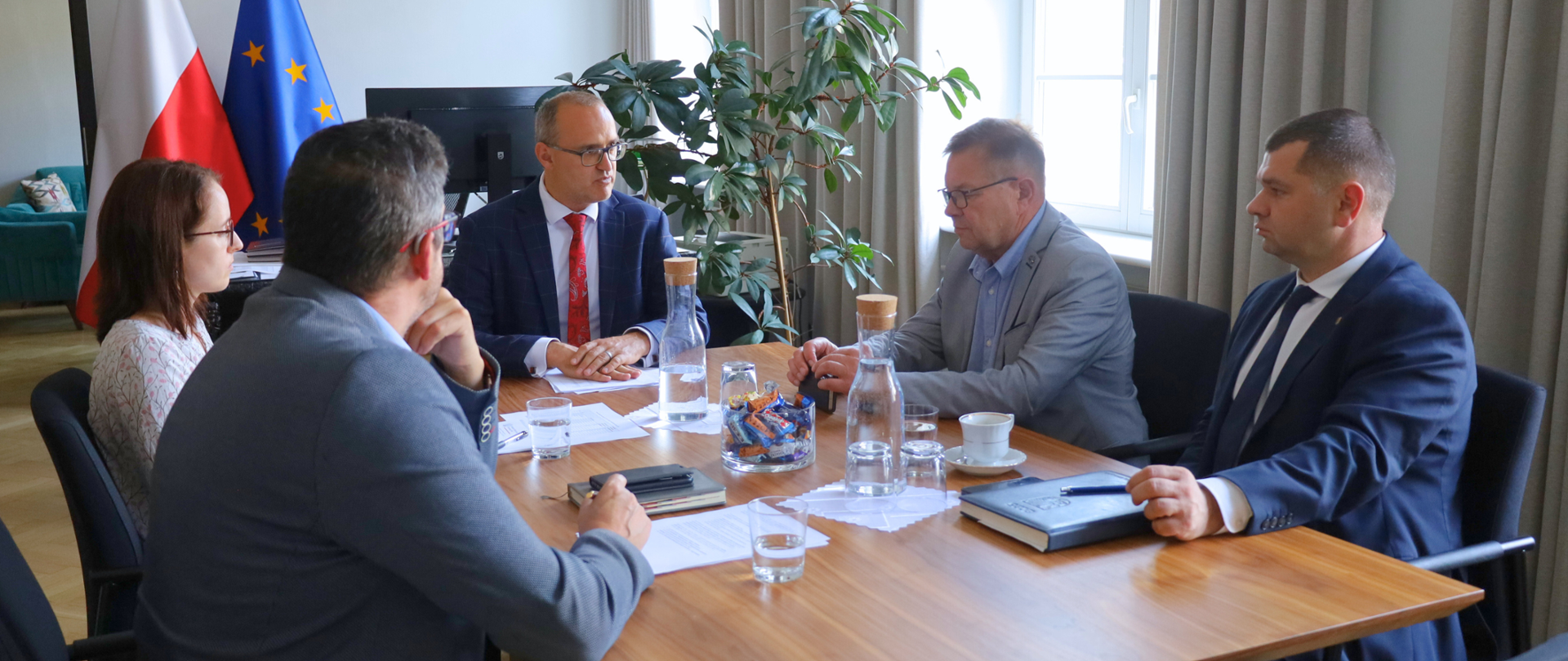 kilka osób siedzi przy stole i dyskutuje