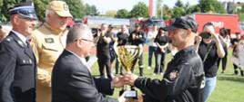 Strażak przyjmujący puchar od organizatorów zawodów OSP
