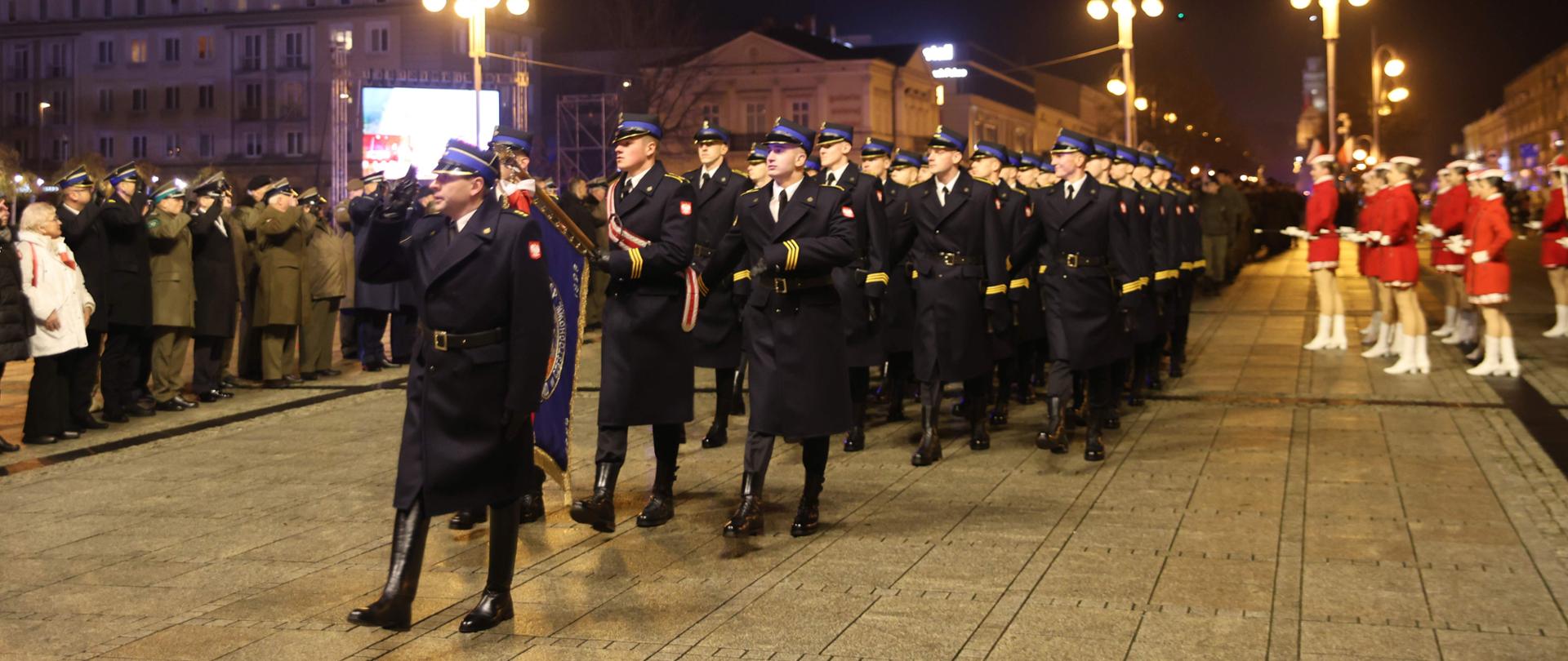 Kompania honorowa Centralnej Szkoły PSP na czele której kroczy poczet sztandarowy prowadzona przez dowódcę maszeruje przez plac