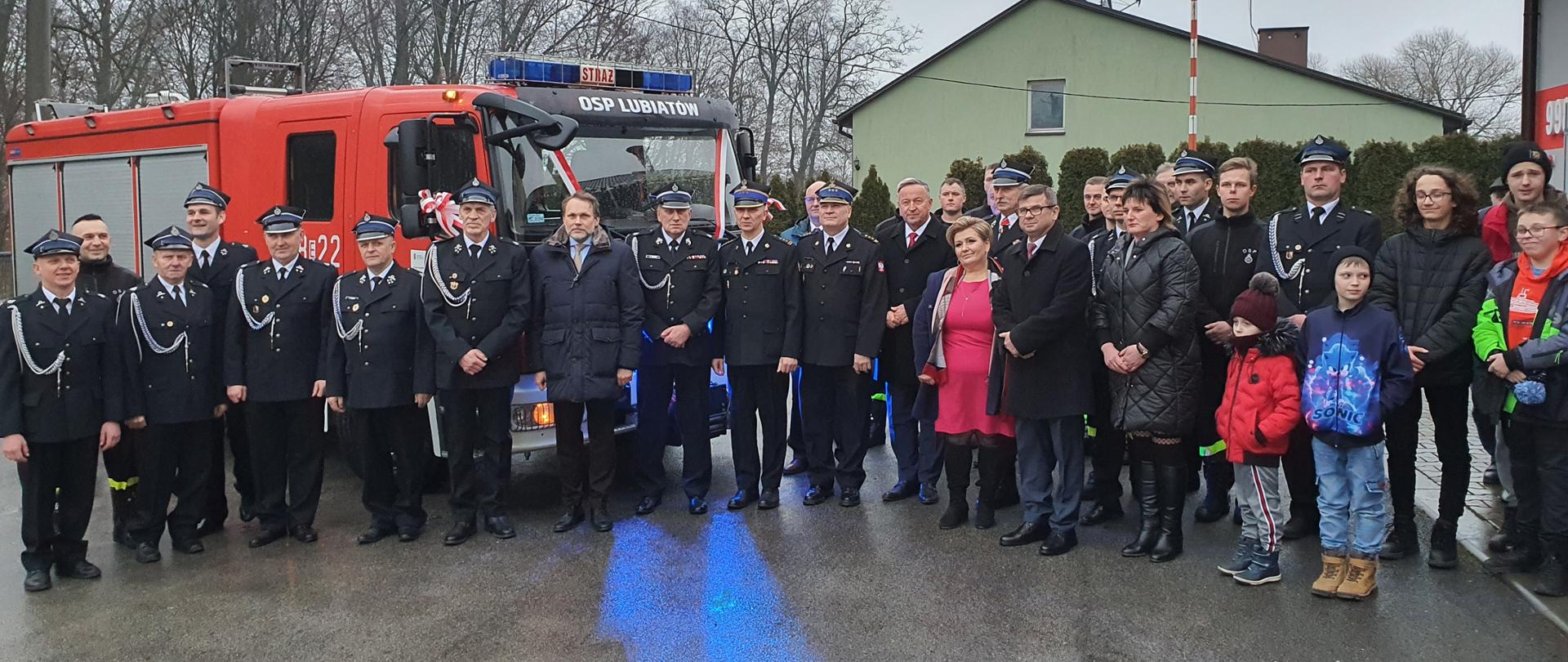 druhowie OSP Lubiatów, strażacy PSP oraz zaproszeni goście pozują do zdjęcia na samochodu gaśniczego