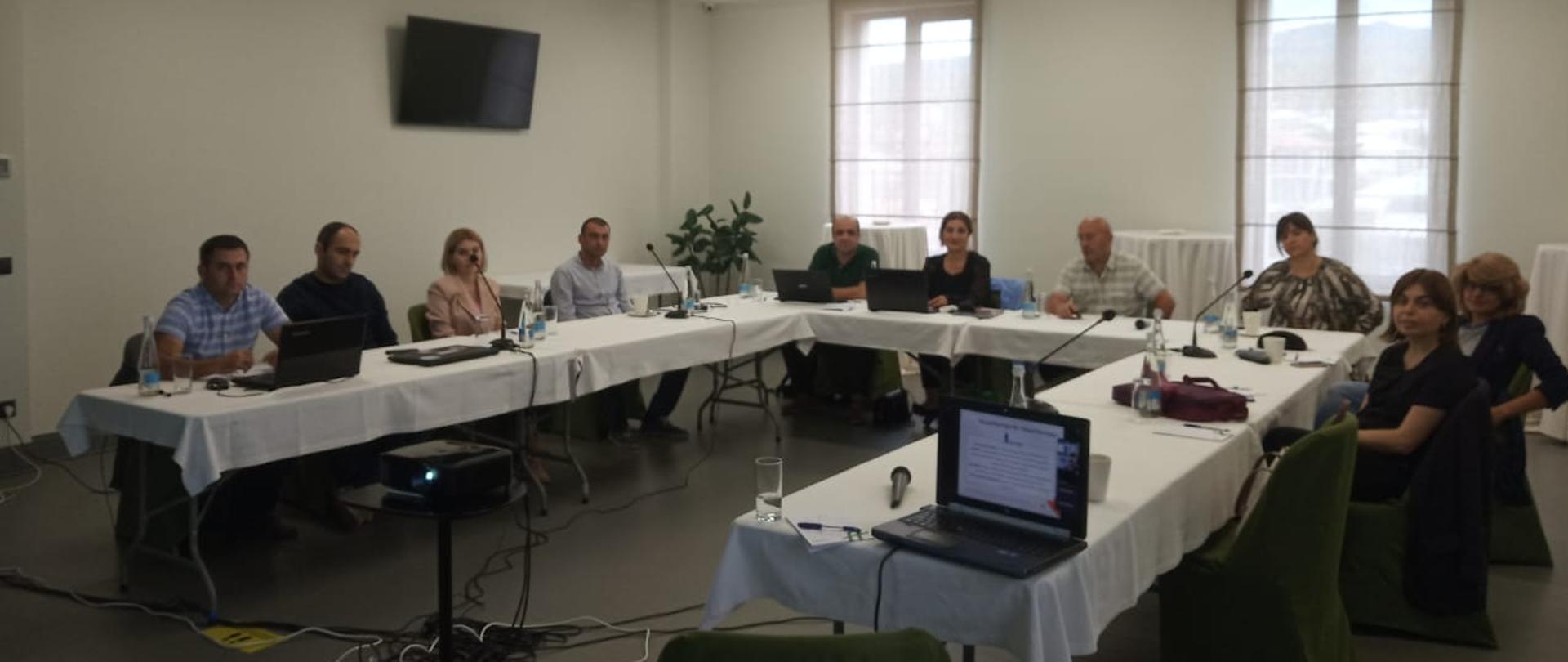 Group of people are sitting close to table and they are listeninig and talking