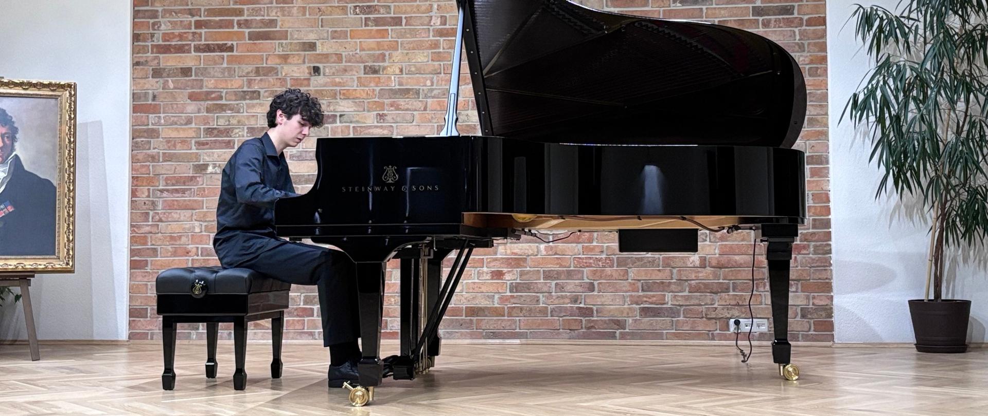 „Młody pianista gra na fortepianie koncertowym w sali ze ścianą z czerwonej cegły.”