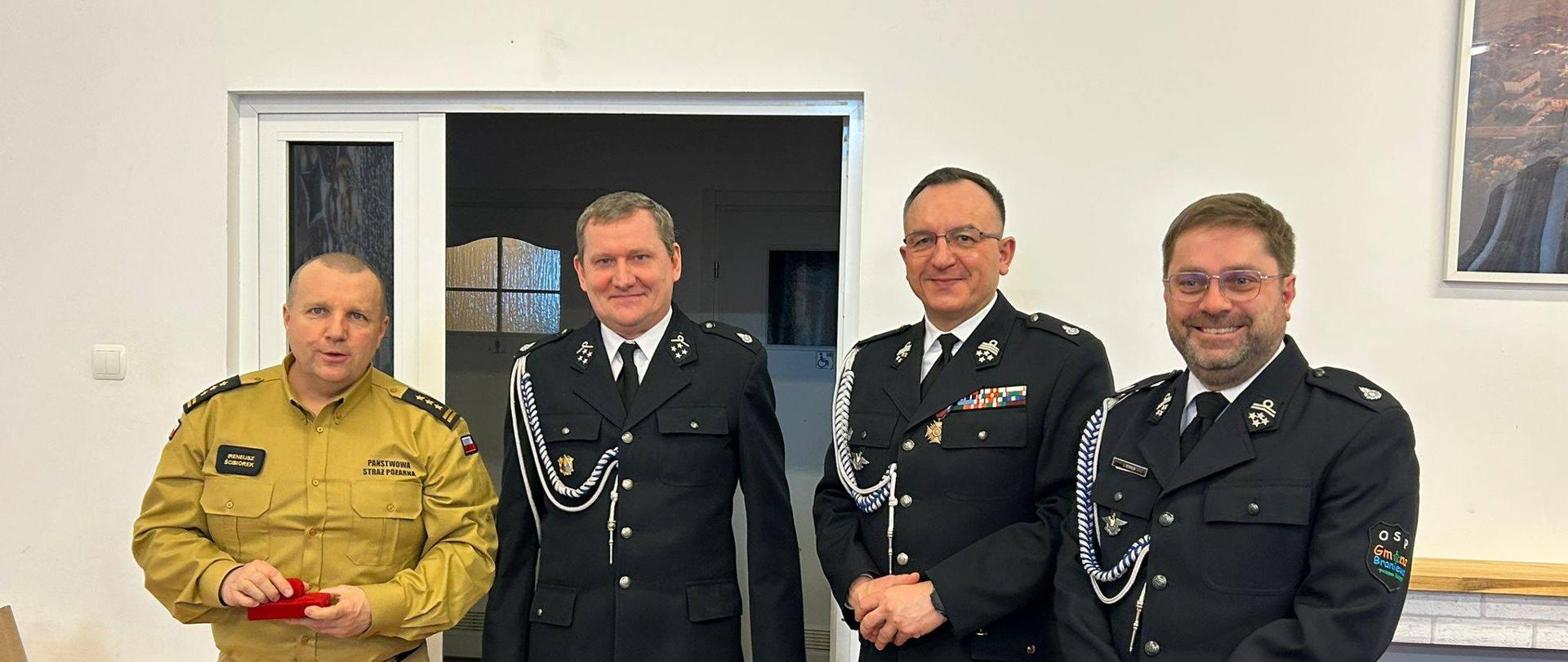 Na zdjęciach czterech strażaków. Trzech w galowych mundurach OSP i jeden z lewej w jasnym mundurze PSP