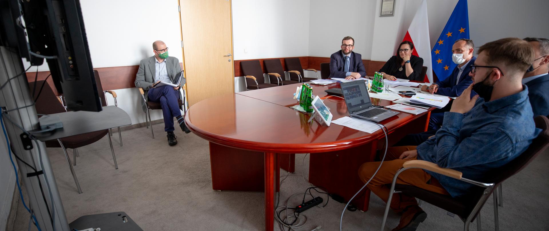Na sali przy okrągłym stole siedzi grupa osób. Od lewej wiceminister G. Puda, obok minister M. Jarosińska-Jedynak.