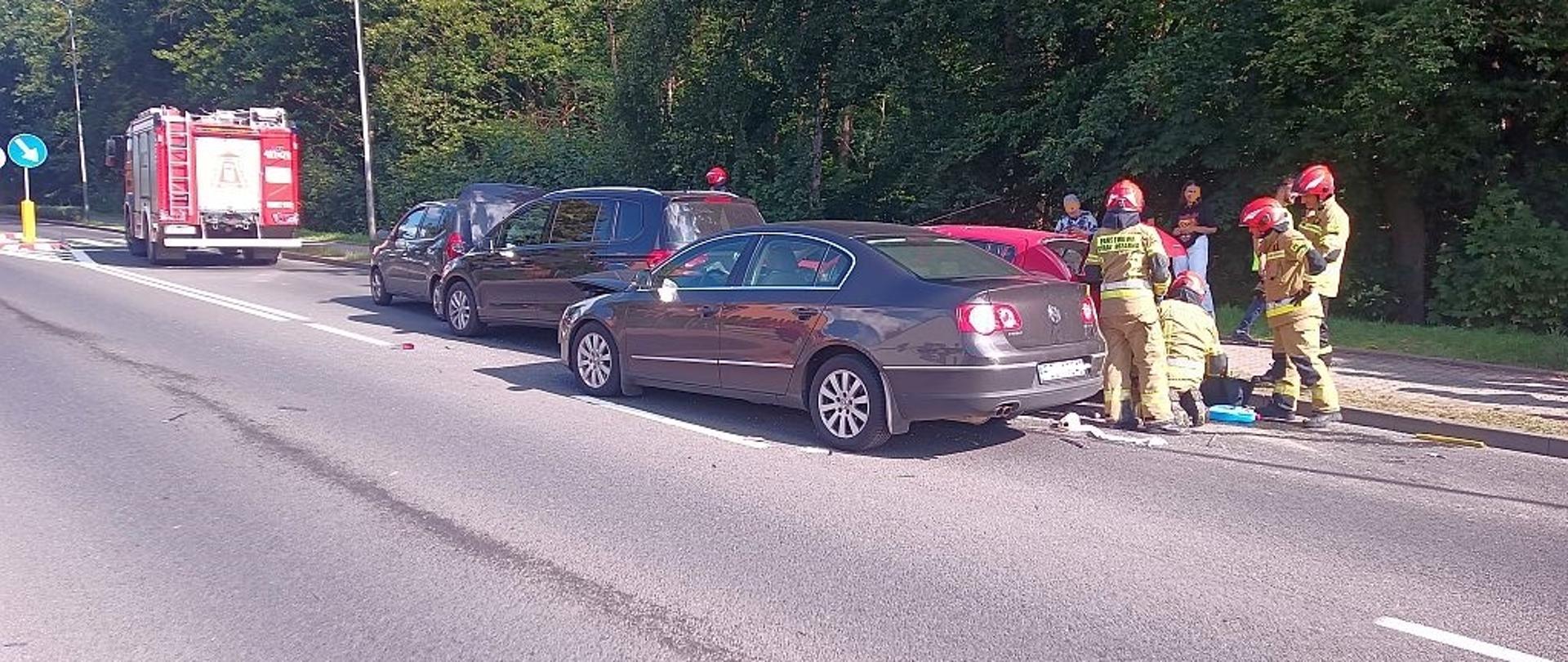 Na zdjęciu znajdują się rozbite auta oraz strażacy którzy wykonują dostęp do pojazdu. 