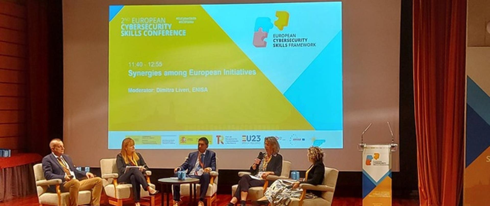 Dyskusja panelowa Synergie inicjatyw europejskich, pięć osób siedzących na scenie przedstawiający stanowisko/prezentację w temacie panelu, widok na widownię 