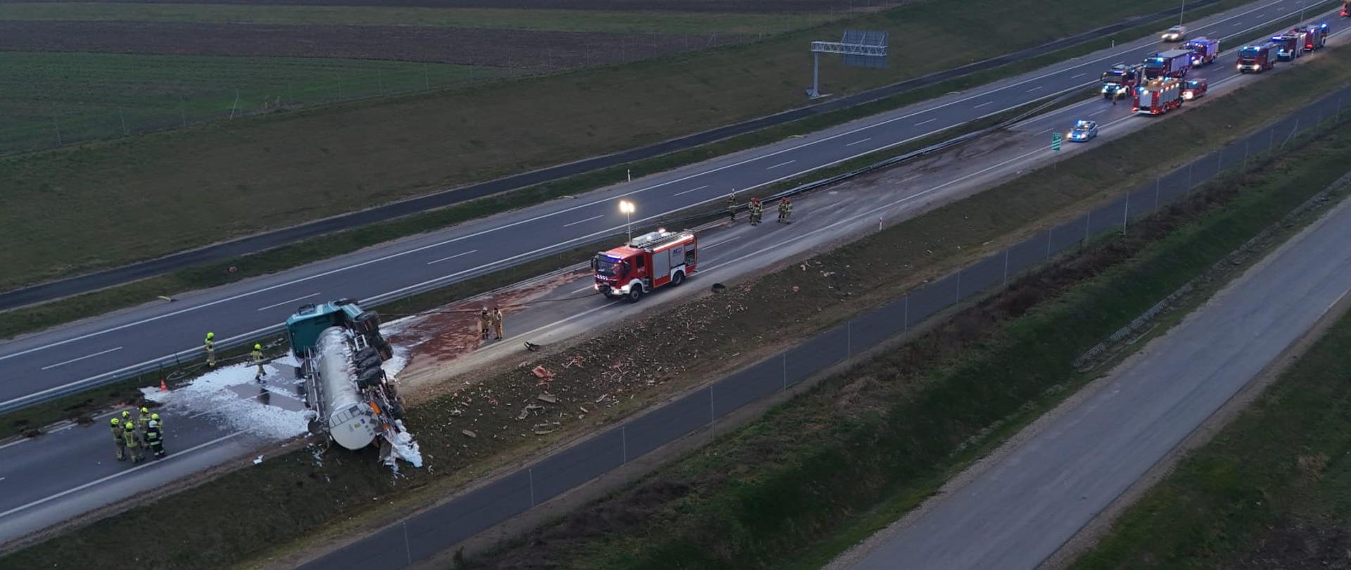 zdjęcie z lotu ptaka ukazujące przewrócony samochód ciężarowy oraz działania strażaków
