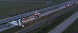 zdjęcie z lotu ptaka ukazujące przewrócony samochód ciężarowy oraz działania strażaków