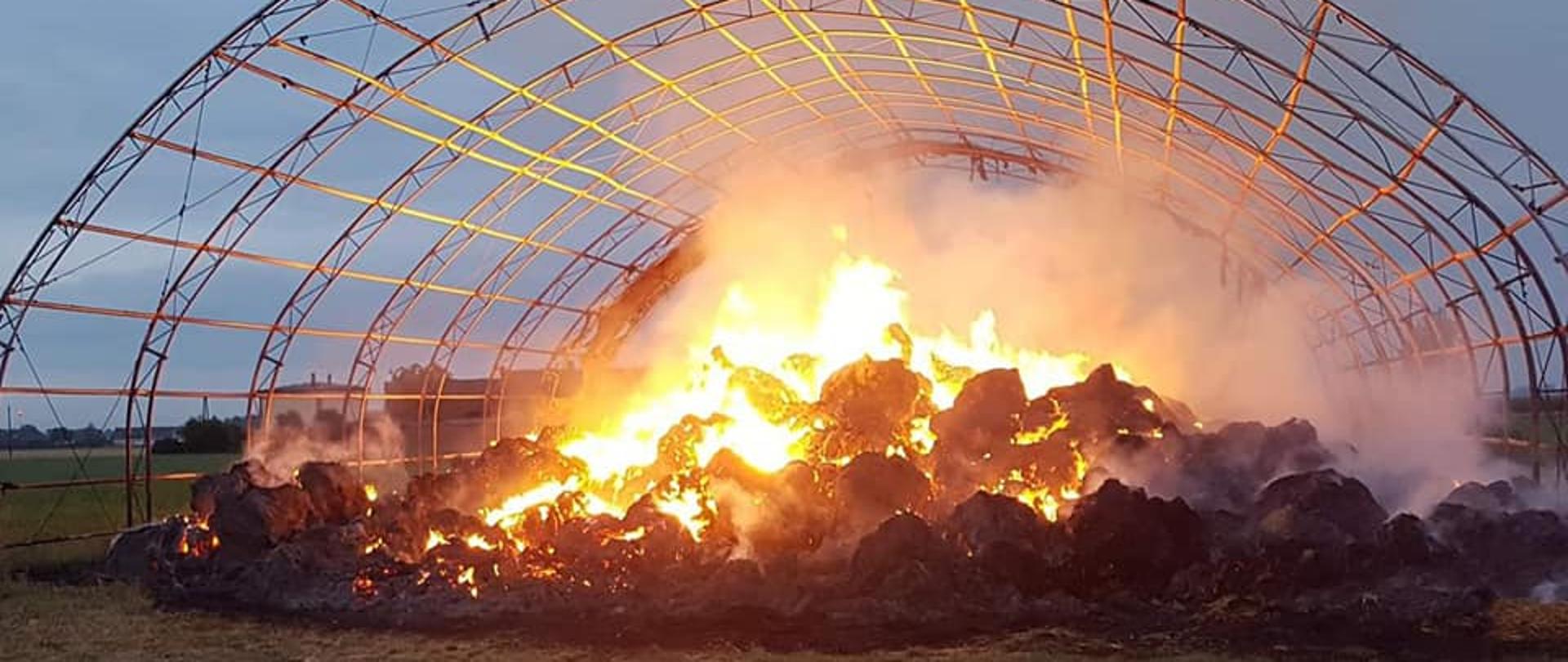 Na zdjęciu znajdują się palące baloty słomy znajdujące się pod wiatą.