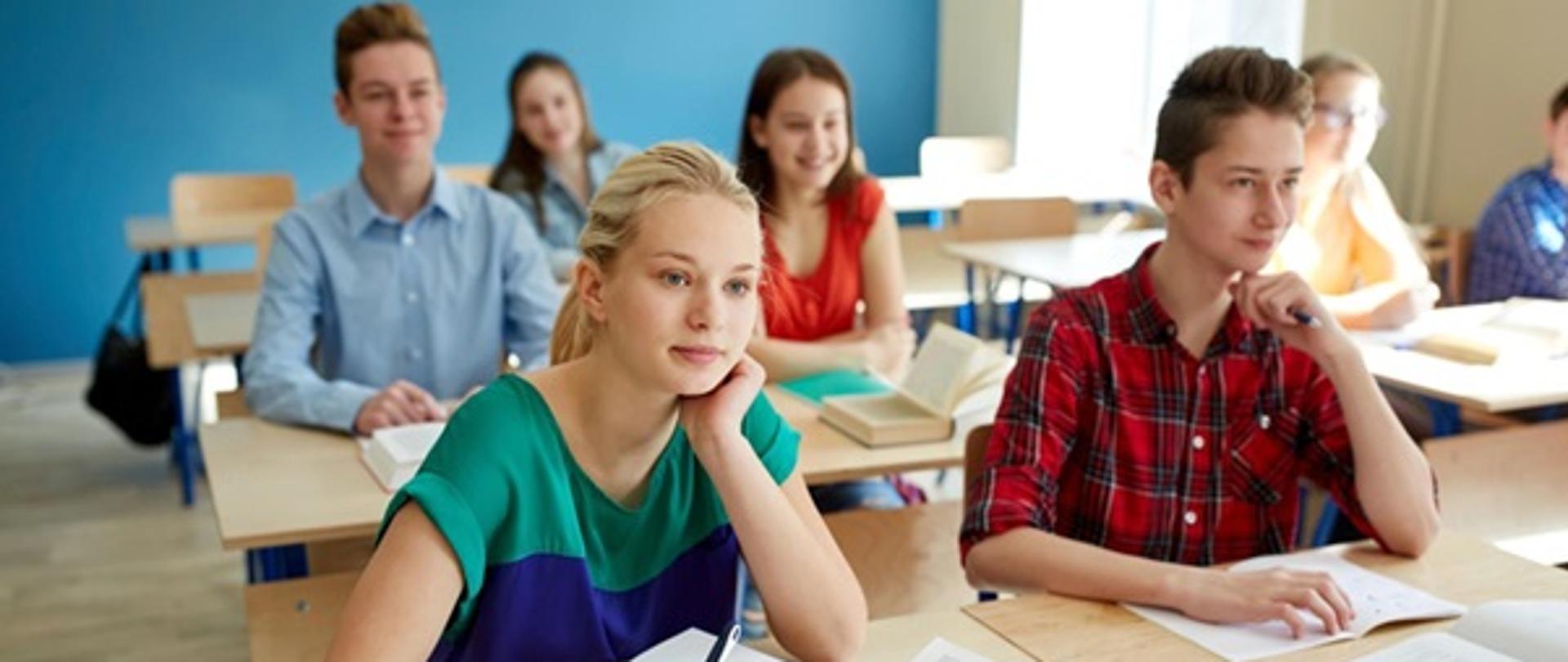 Zdjęcie przedstawiające klasę w szkole pełną uczniów siedzących w ławkach.