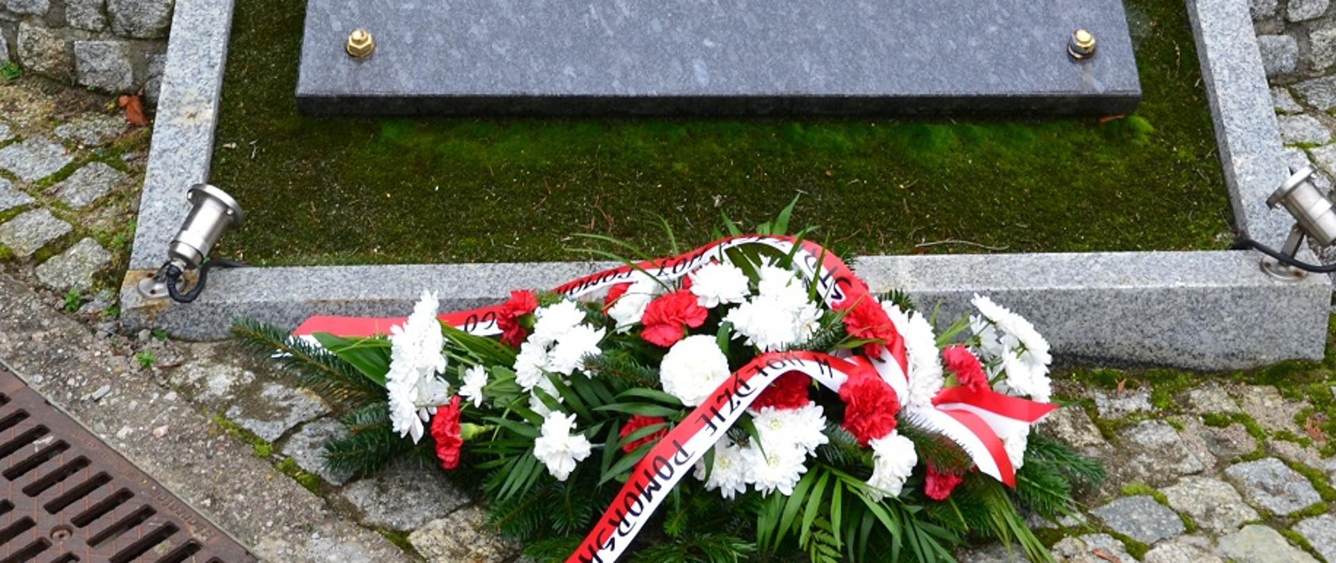 Pod pomnikiem w hołdzie pomorskim strażakom leży wiązanka oraz pali się znicz.