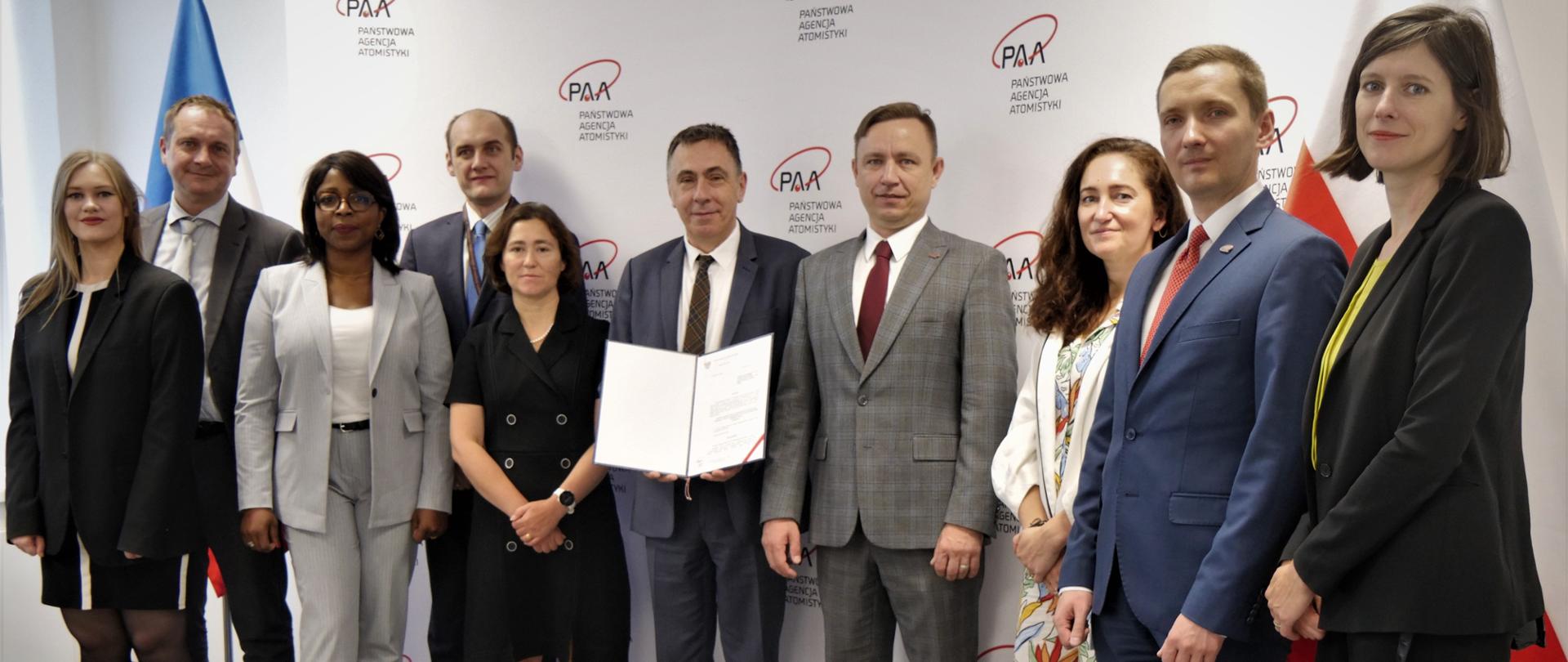 Przedstawiciele PAA, IRSN oraz Ambasady Francji w Warszawie podczas spotkania w siedzibie PAA. W tle flagi Polski oraz Francji, a także ścianka w logo PAA