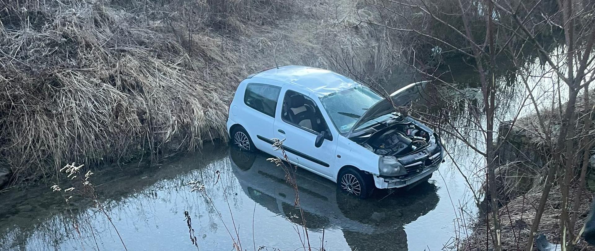Samochod osobowy stoi na kołach w potoku