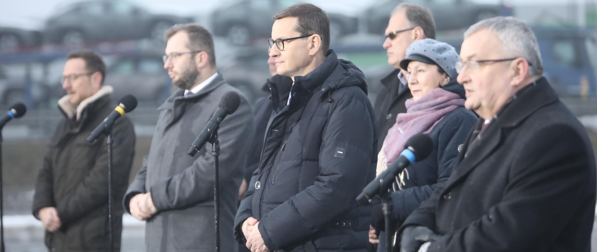 uczestnicy uroczystości stoją przy mikrofonach