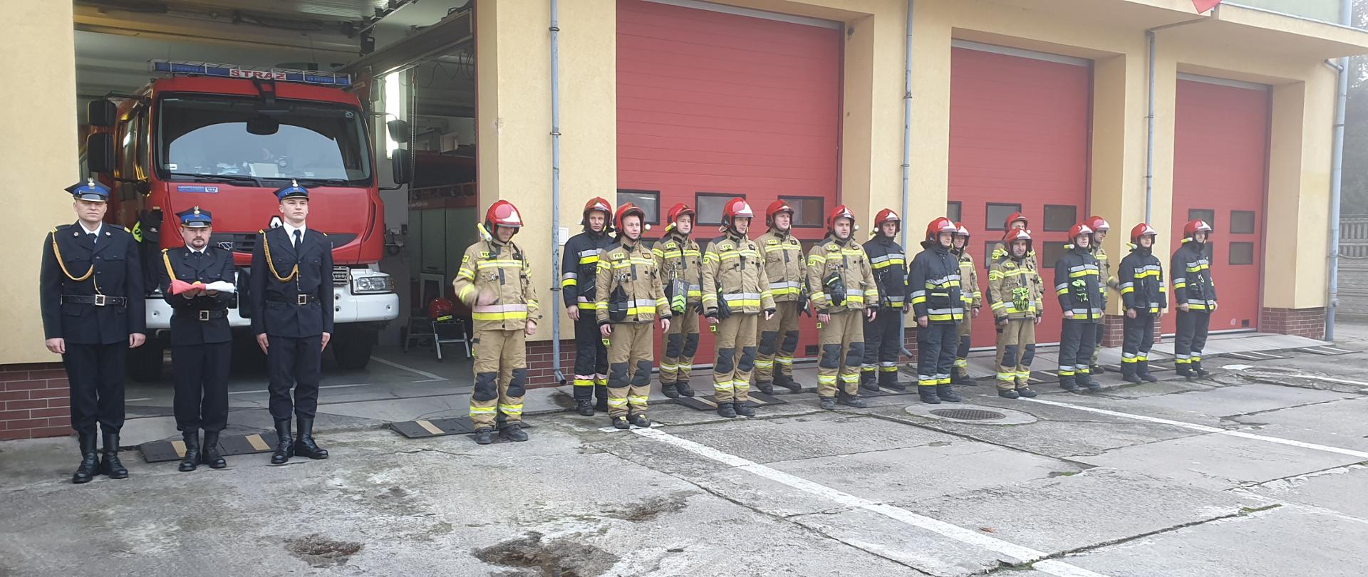 Zdjęcie przedstawia poczet flagowy i zmianę służbową stojących przed budynkiem komendy