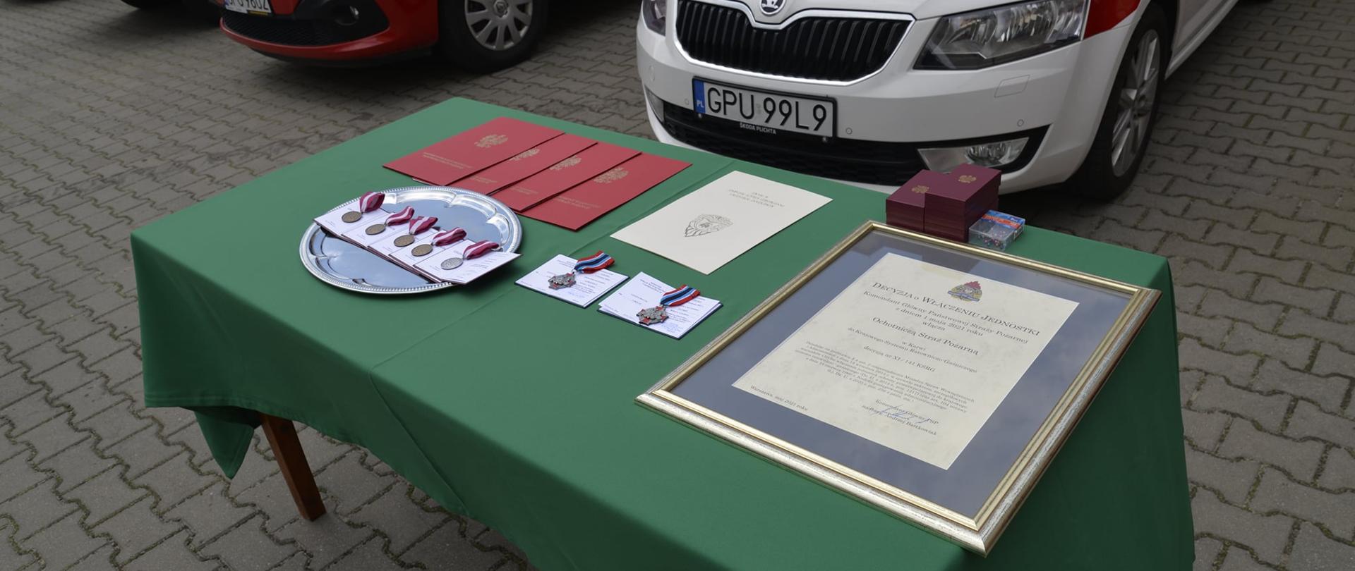 Zdjęcie przedstawia medale oraz odznaki leżące na stole.