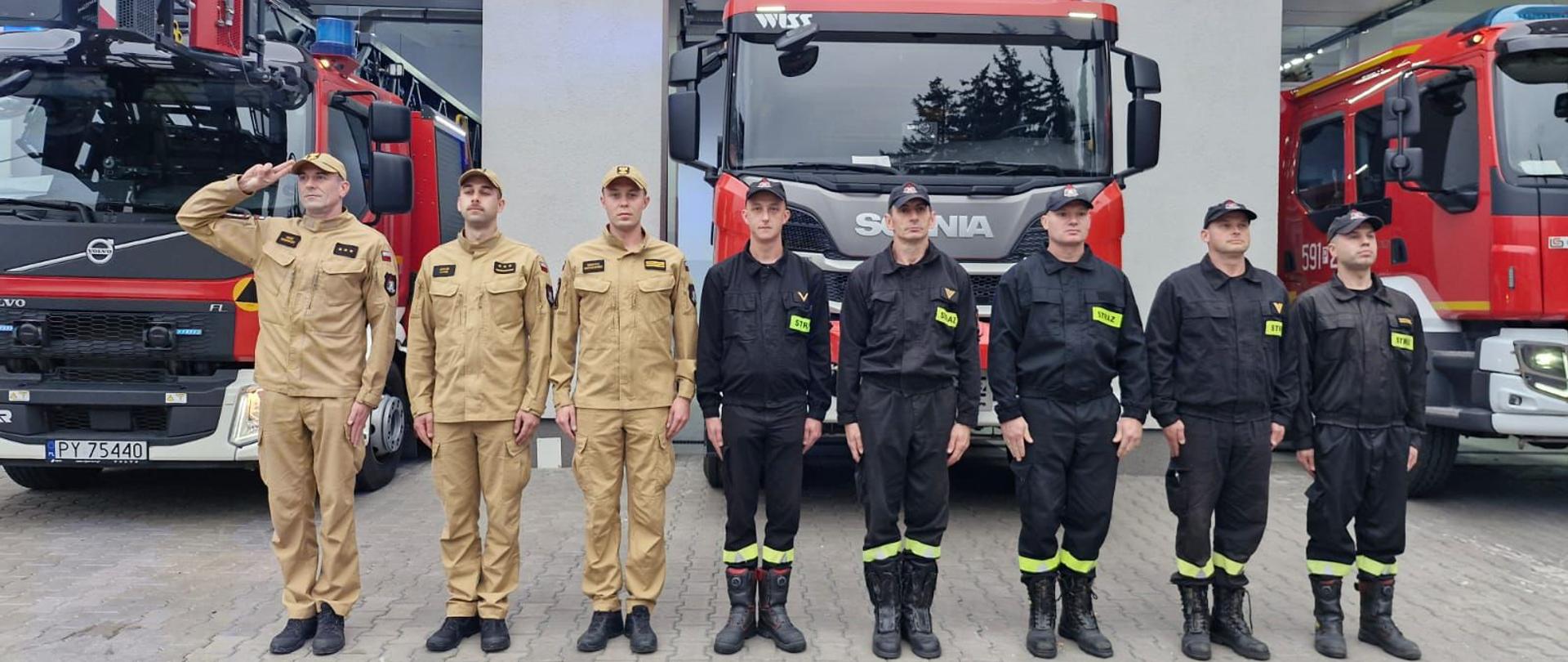 Strażacy na tle samochodów i garażu oddają hołd