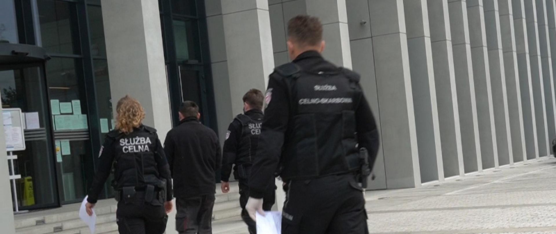 Troje funkcjonariuszy KAS prowadzi podejrzanego.