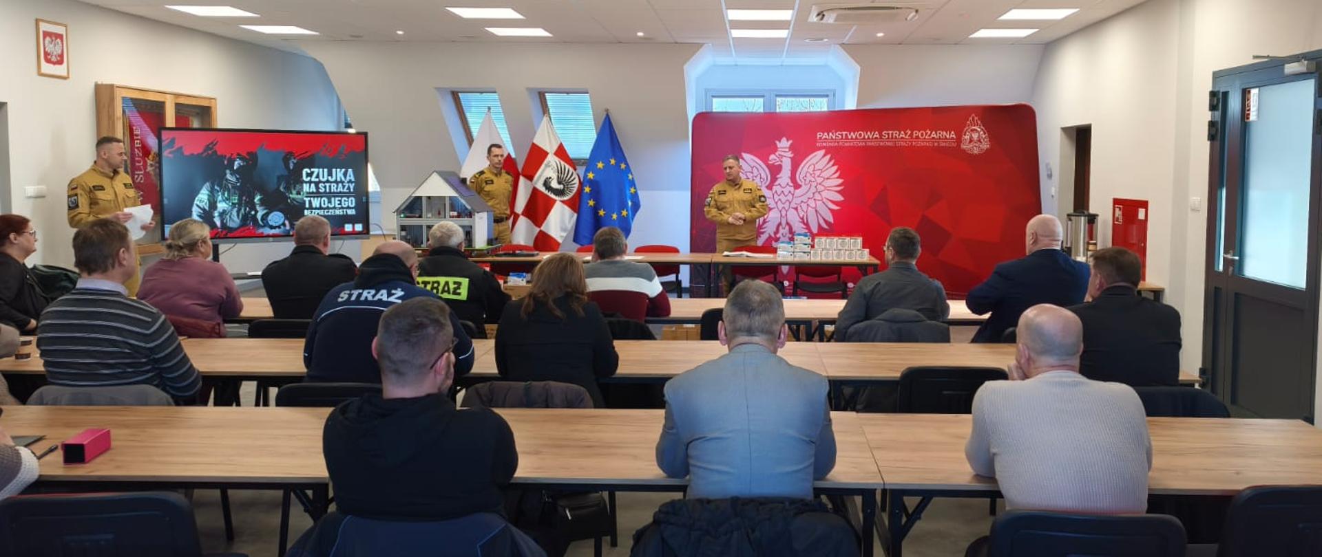 Komendant prezentuje czujki tlenku węgla i dymu które zostaną przekazane na spotkaniu