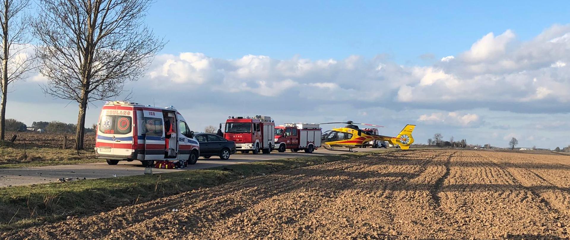 Na zdjęciu widać 2 samochody pożarnicze, ambulans oraz helikopter LPR