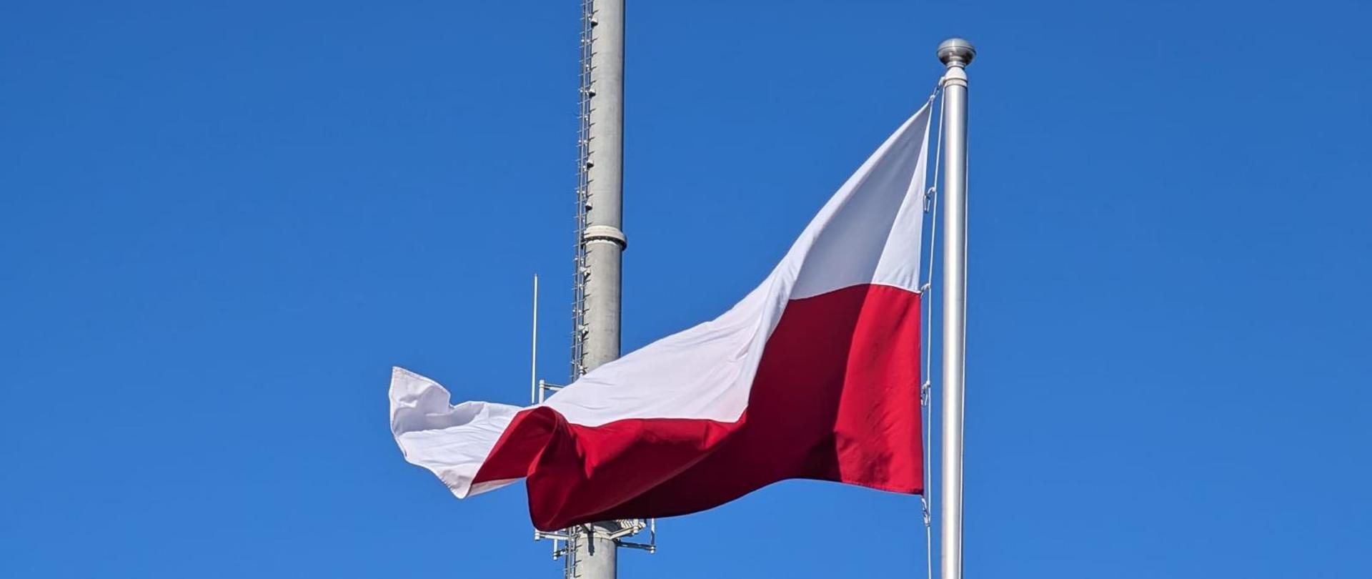 Flaga polski zawieszona na maszcie.