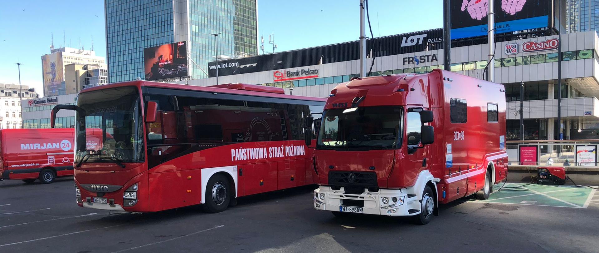 Na zdjęciu widać parking przed Dworcem Centralnym, na którym stoi autobus straży pożarnej oraz samochód dowodzenia i łączności. W tle widoczna zabudowa centrum Warszawy m. in. Hotel Marriott 