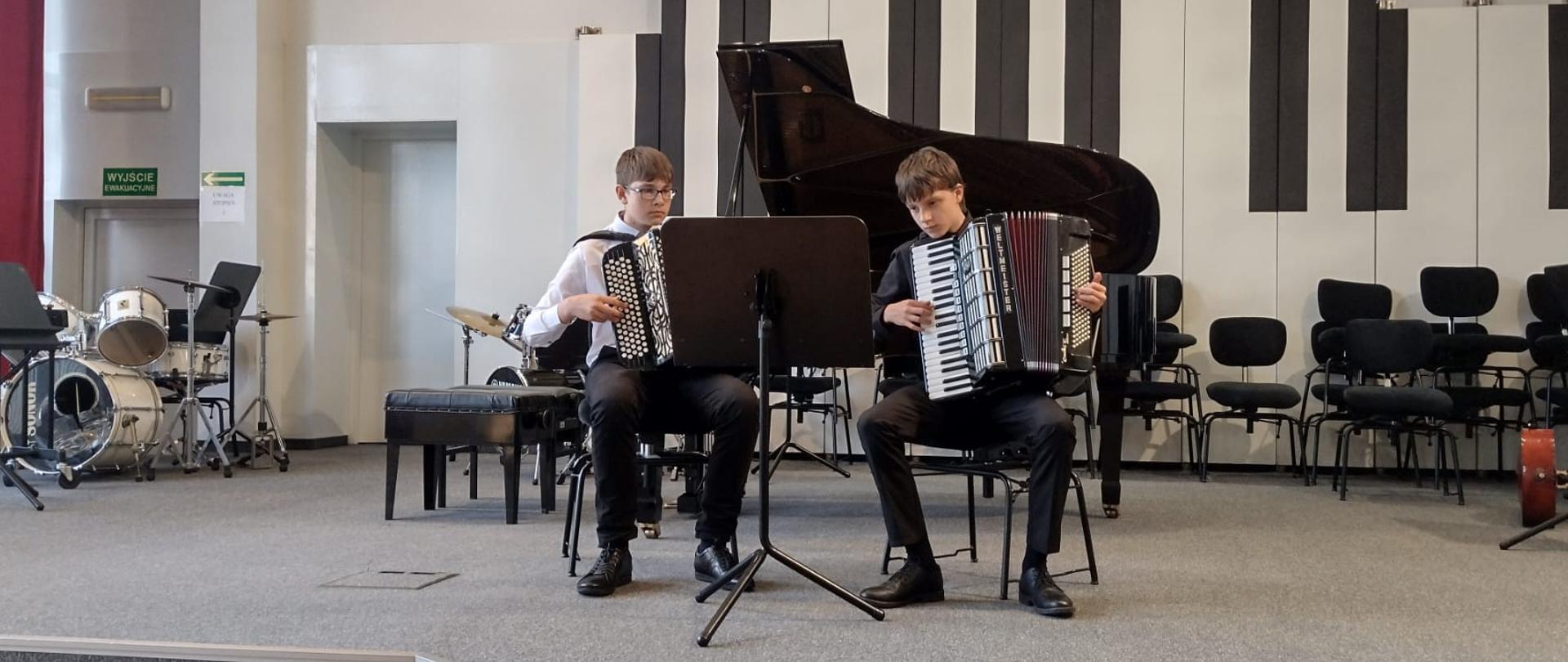 Dwóch chłopców gra na akordeonach.