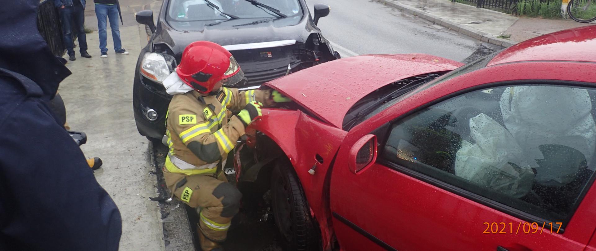 Zdjęcie przedstawia strażaka odcinającego zasilanie w pojeździe. 