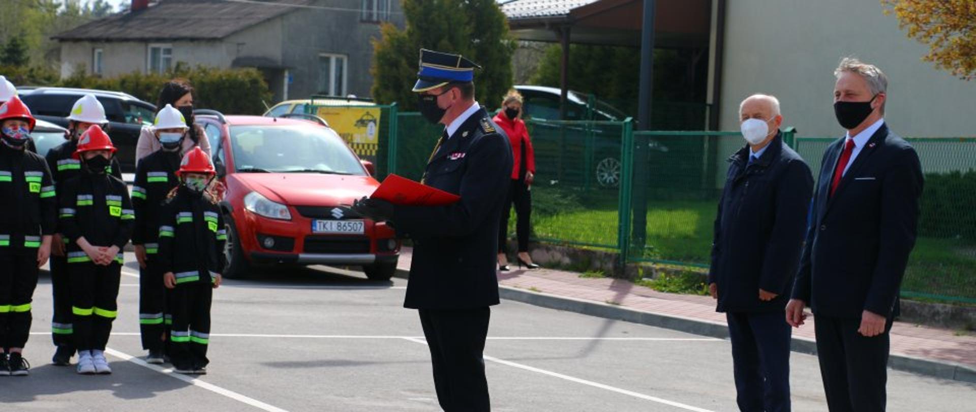 Zdjęcie przedstawia Komendanta Miejskiego PSP w Kielcach składającego życzenia strażakom. Za nim Burmistrz miasta i gminy Morawica oraz Wojewoda Świętokrzyski.
