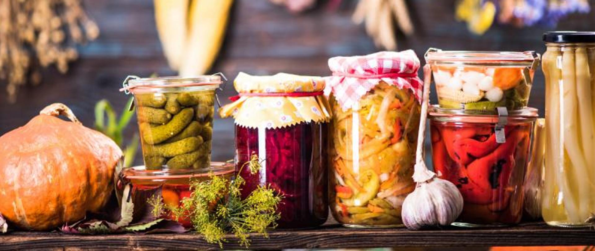 Na zdjęciu znajdują się przetwory oraz warzywa sezonowe (dynia, ogórki, czosnek, koper).