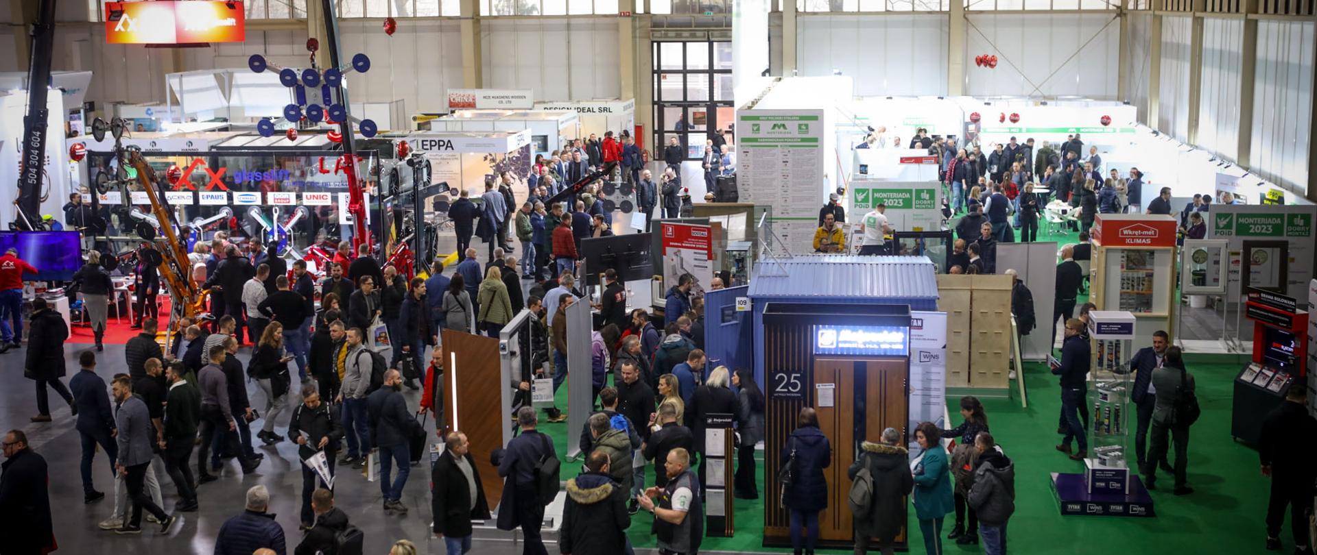 Widok z góry na zatłoczoną halę wystawową podczas targów BUDMA 2024, z licznymi stoiskami firm budowlanych i odwiedzającymi.