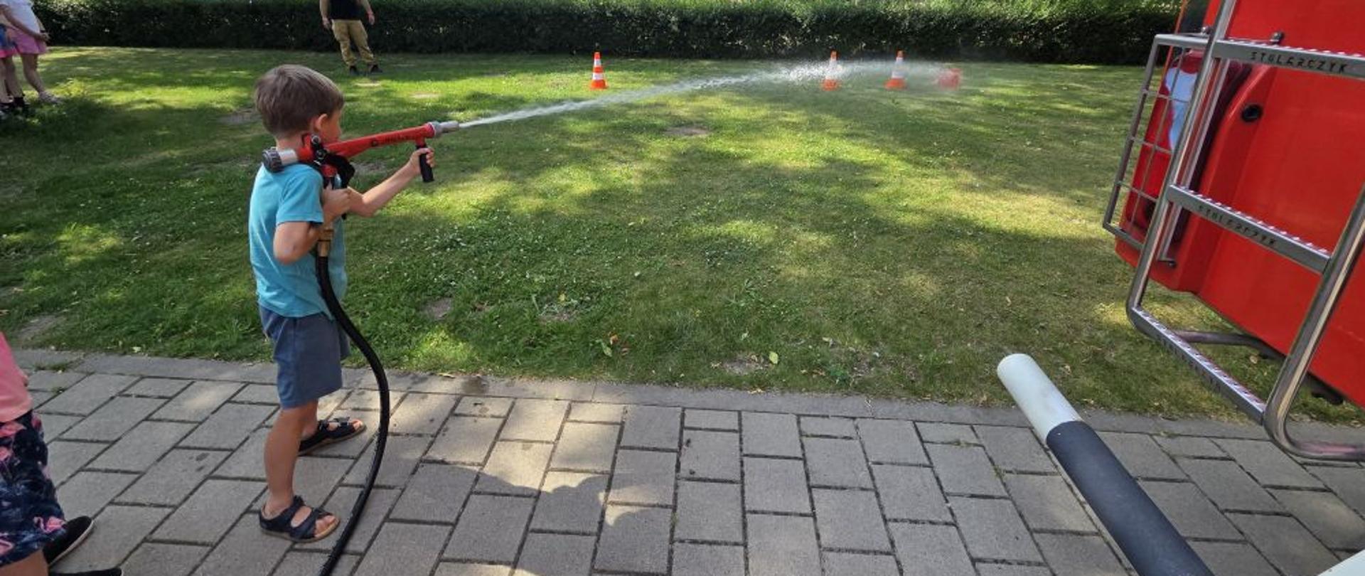 Chłopiec strąca pachołki wodą