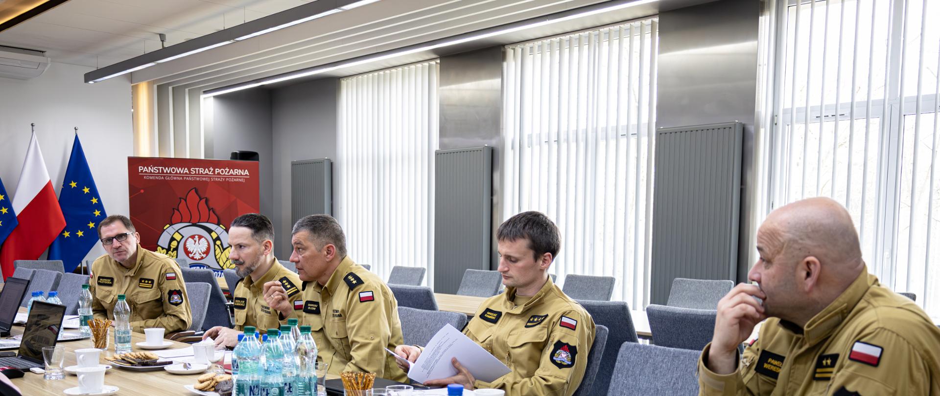 Funkcjonariusz PSP siedzi przy stole podczas spotkania