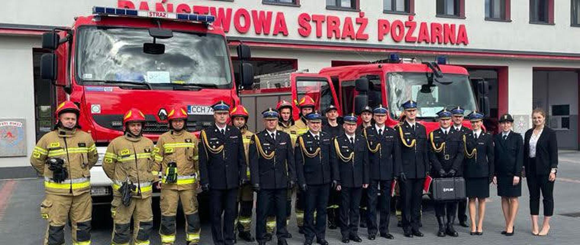 Na zdjęciu znajdują się funkcjonariusze i pracownicy cywilni KP PSP w Chełmnie oraz Zastępca Komendanta Wojewódzkiego PSP w Toruniu na wspólnym zdjęciu. Zdjęcie wykonano przed budynkiem komendy. 